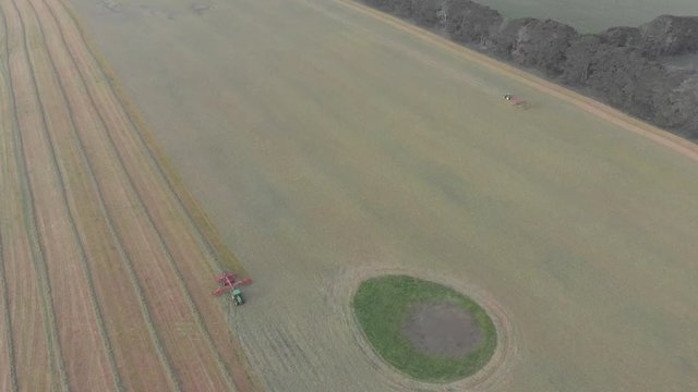 High distant aerial shot above spreader & rake working in huge paddock.