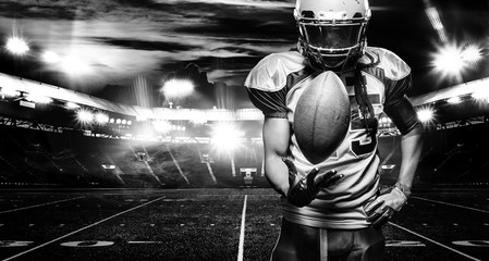 American football player, athlete in helmet with ball on stadium. Black and white photo. Sport...