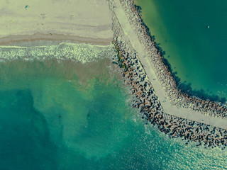 An aerial view, high up, and directly above the beach and jetty at the Santa Cruz Harbor
