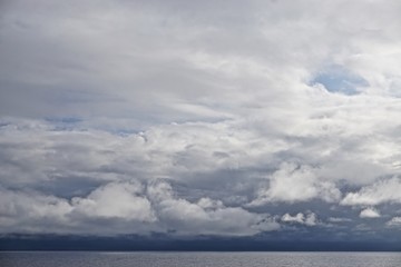Fototapeta na wymiar The sun pierces through gathering storm clouds over the Gulf of Alaska.