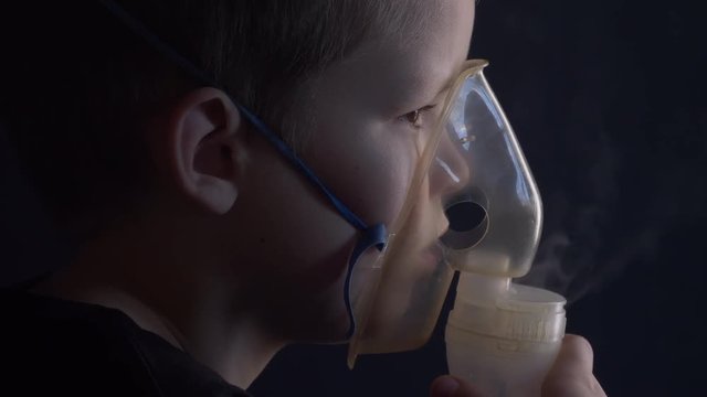 Caucasian blonde boy inhales couples containing medication to stop coughing. Medical procedures. Inhaler. Respiratory medicine. Bronchitis, asthmatic health equipment. Concept of home treatment.