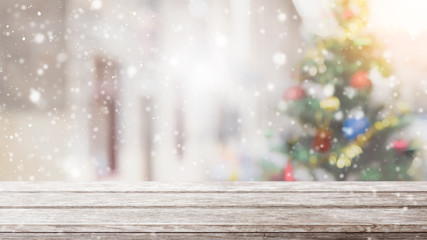 Empty wood table top on blur with bokeh Christmas tree background with snowfall - can be used for display or montage your products.