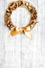 Creative, unusual christmas wreath made of thread, dry fruits and nuts on white wooden background top view space for text