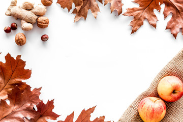 Autumn nature concept. Background with autumn symbols. Brown leaves, apple, nuts on white background top view copy space frame