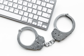 Cyberfraud concept. Handcuff near keyboard on white background top view copyspace closeup