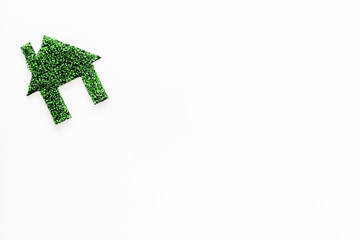 Green eco energy concept. House silhouette made of green grass on white background top view copy space