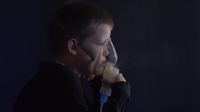 Caucasian blonde boy inhales couples containing medication to stop coughing. Medical procedures. Inhaler. Respiratory medicine. Bronchitis, asthmatic health equipment. Concept of home treatment.