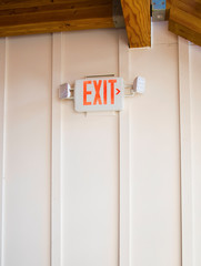 Exit sign on white wall with wooden carcas