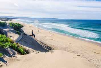 Man Sitting on Pipe looking at Sand Beach