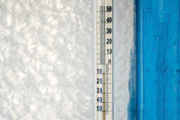 thermometer shows minus temperature against the background of a frozen window
