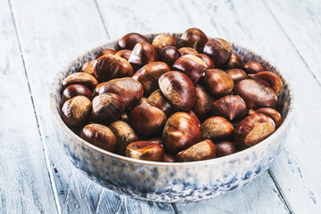 Roasted chestnuts served in chestnut pan on an old table