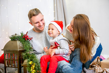Happy family, father, mother and son, in the morning in bedroom decorated for Christmas. They open presents and have fun. New Year's and Christmas theme. Holiday mood