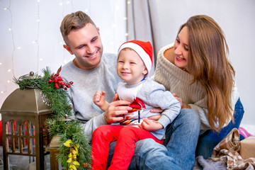 Happy family, father, mother and son, in the morning in bedroom decorated for Christmas. They open presents and have fun. New Year's and Christmas theme. Holiday mood