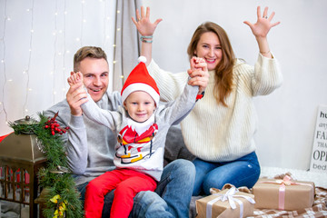 Happy family, father, mother and son, in the morning in bedroom decorated for Christmas. They open presents and have fun. New Year's and Christmas theme. Holiday mood