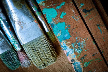 Dirty artist oil paint brushes in stacks on wooden background - landscape orientation  