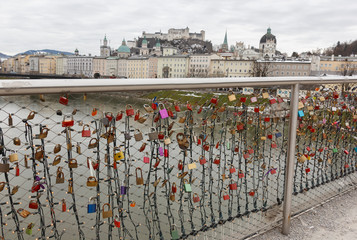 Naklejka premium panoramic winter view of the historic center of Salzburg Austria surrounded by the Alps covered with snow in a foggy haze from the bridge with padlocks