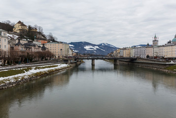 panoramic winter view of the historic center of Salzburg Austria surrounded by the Alps covered with snow in a foggy haze from the bridge with padlocks