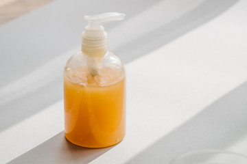 Clear plastic bottle with organic cosmetic product from above. Direct light and shadows. Beauty blogging minimalism concept