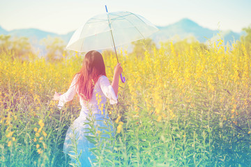 Women feeling free running to the yellow meadow. Happiness of women running to the field holding a umbrella outdoor.