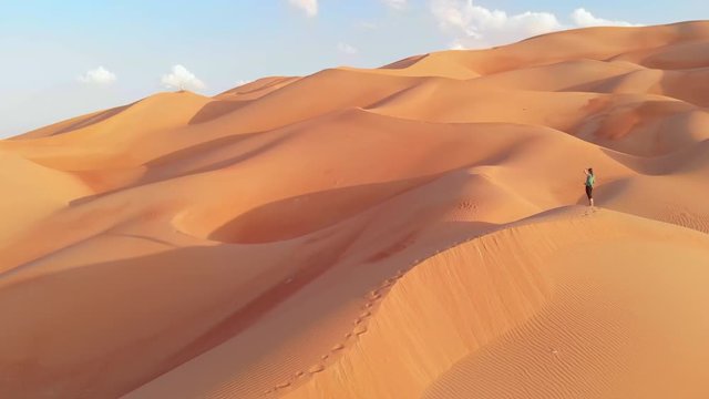 person walking in the dunes of Liwa desert, part of Emty Quarter desert, the largest continuous sand desert in the world
