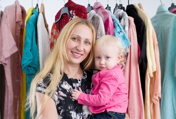 Woman with baby  chooses clothes in the wardrobe closet at home