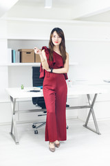 Portrait of beautiful smart Asian business woman standing in front of the table in workplace.