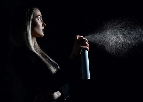 Woman hold hair sprey on black background 