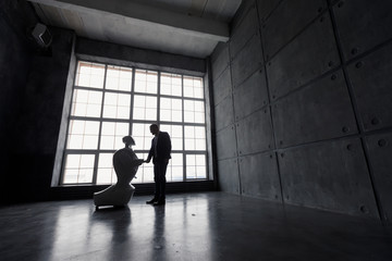 A man communicates with a robot, with cardboard box in hand. delivery concept. silhouette of the robot against the window