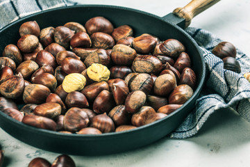 Roasted chestnuts served in chestnut pan on an old table