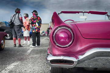 A bumper of an old vintage pink car at a car show.