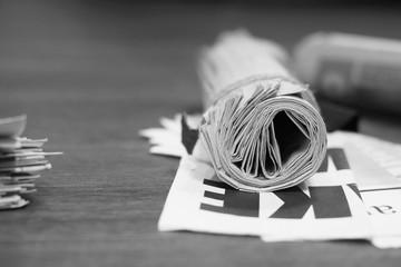 Rolled fresh morning newspapers on the table at office. Latest financial and business news in daily paper. Pages with information (headlines, articles, photos, text). Folded and stacked journals