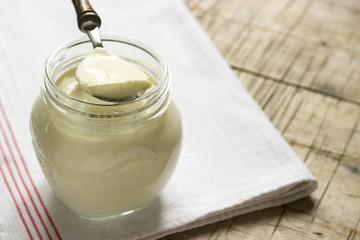 Homemade yogurt in a jar and spoon on a wooden background. Rustic style.