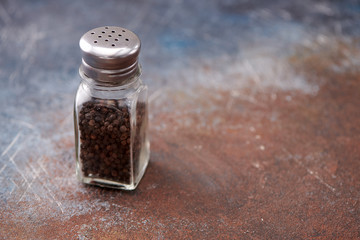 black pepper in the pepper shakers on dark background