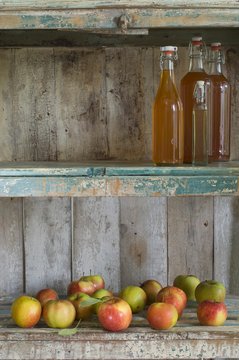 Several bottles of apple juice and apples (variety 'Jonagold') in rustic cupboard