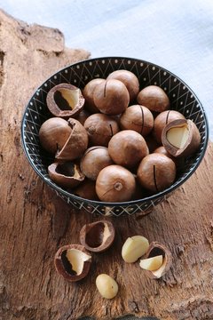Macadamia nuts, whole and cracked on a piece of bark