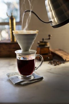 Hot water pouring through coffee filter into coffee cup