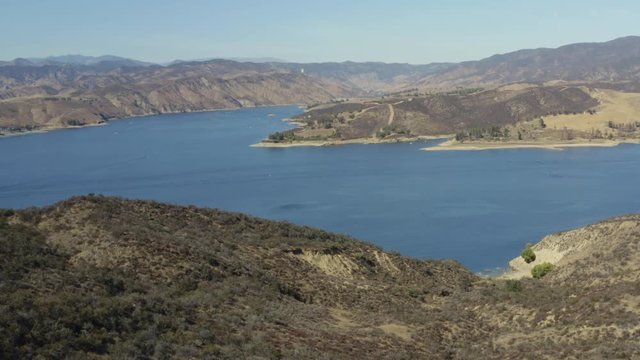 A blue lake in between hills with power boats and kayaks