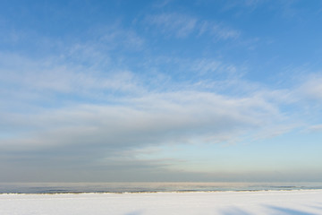 Winter shoreline of baltic sea with snow and ice under blue sky with clouds, selective focus
