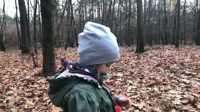 Little girl walking in the forest and blowing  whistle.