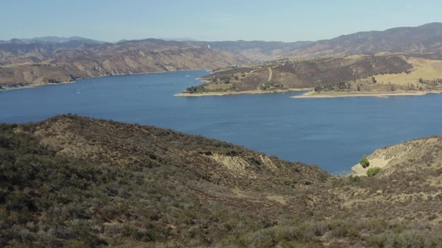 A blue lake in between hills with power boats and kayaks