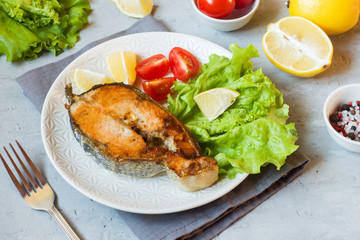 Steak baked salmon fish on a plate with fresh vegetables.