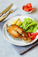 Steak baked salmon fish on a plate with fresh vegetables.