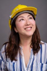 Mature Asian businesswoman construction worker wearing hardhat