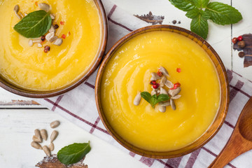 Pumpkin soup mashed with spices in wooden bowls on light boards.