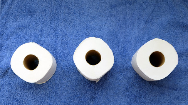 Flat Lay Of Three Toilet Paper Rolls On A Blue Towel Background