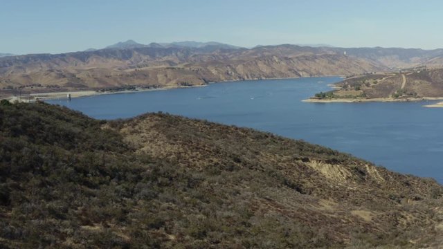 A blue lake in between hills with power boats and kayaks