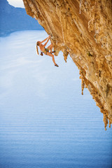 Young female rock climber on challenging route on cliff
