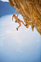 Young female rock climber on challenging route on cliff