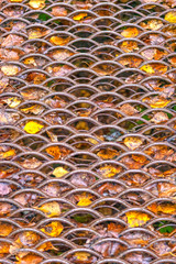 Rusty cellular metal sheet with autumn leaves between cells background