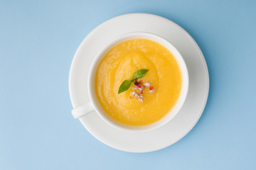 Pumpkin soup mashed with spices in a Cup on a blue background.